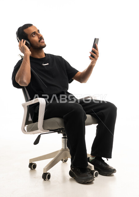 رجل سعودي يستخدم سماعات الرأس والهاتف في الاستوديو