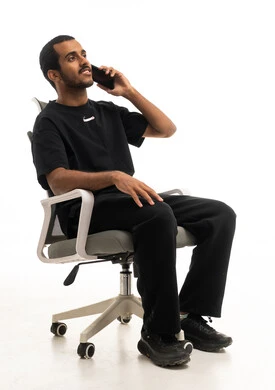 شاب سعودي يتحدث بالهاتف جالساً على كرسي مكتب