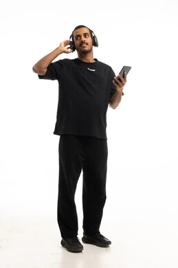 شاب عربي بسماعات وهاتف ذكي بخلفية بيضاء