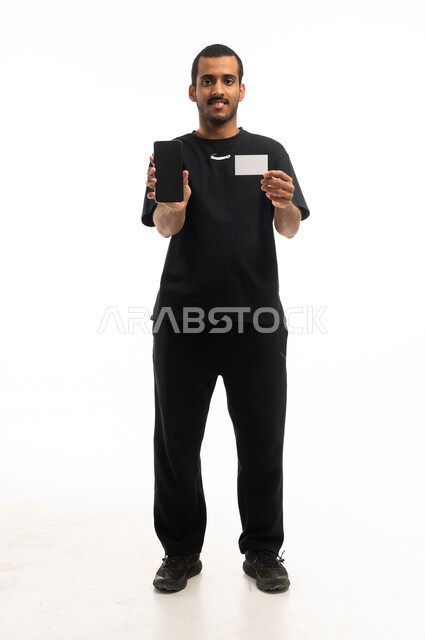 رجل سعودي يحمل هاتفاً ذكياً وبطاقة فارغة في الاستوديو