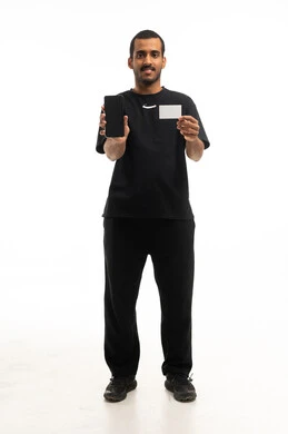 رجل سعودي يحمل هاتفاً ذكياً وبطاقة فارغة في الاستوديو