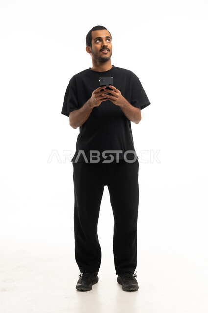 رجل سعودي يمسك هاتف ذكي وينظر للأعلى