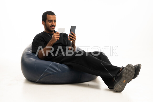 رجل عربي يستخدم هاتف ذكي وبطاقة ائتمان للتسوق