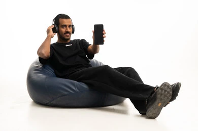 رجل سعودي يحمل هاتفا ذكيا ويرتدي سماعات رأس