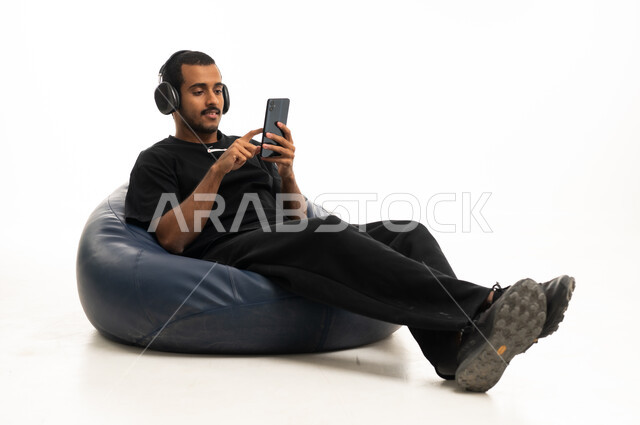 Saudi Man on Beanbag Using Phone and Headphones