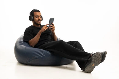 شاب سعودي يستخدم الهاتف والسماعات على كرسي بين باج