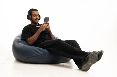 شاب عربي يستخدم الهاتف وسماعات الرأس على مقعد مريح