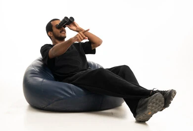 رجل سعودي يستخدم المنظار على كرسي استرخاء