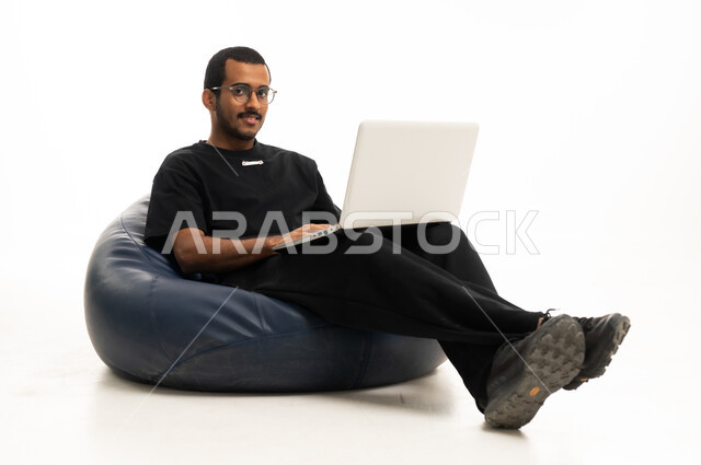 رجل سعودي يستخدم اللابتوب على خلفية بيضاء