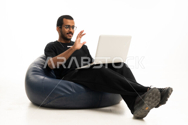 رجل سعودي يستخدم اللابتوب جالسًا على كرسي محشو