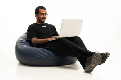 شاب سعودي يعمل على لابتوب بخلفية بيضاء