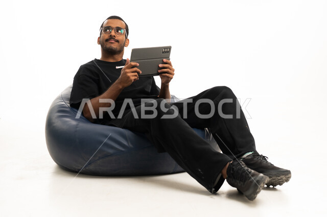 رجل سعودي مع جهاز لوحي على مقعد استرخاء