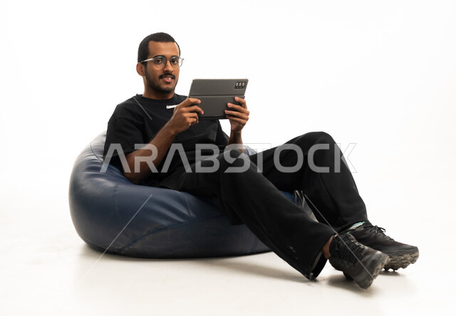 شاب سعودي يستخدم جهاز لوحي على مقعد استرخاء