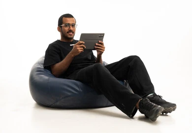 شاب سعودي يستخدم جهاز لوحي على مقعد استرخاء