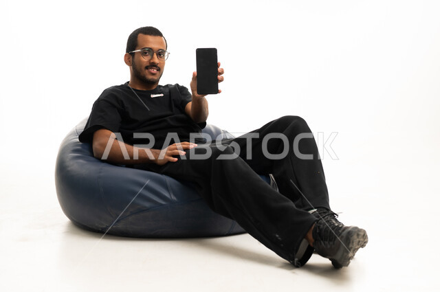 شاب عربي جالس يمسك هاتف ذكي في استوديو