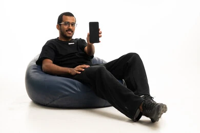 شاب عربي جالس يمسك هاتف ذكي في استوديو