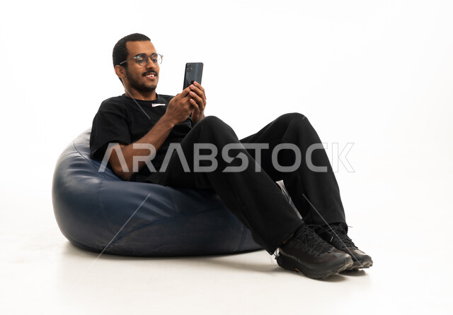 شاب عربي يجلس على مقعد محشو يستخدم الهاتف الذكي