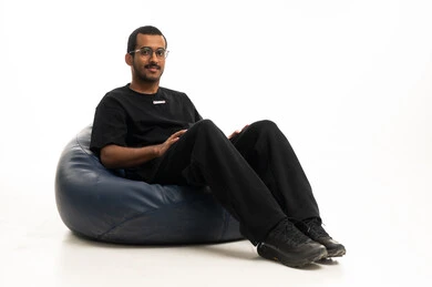 شاب سعودي يجلس على بين باج أزرق بخلفية بيضاء