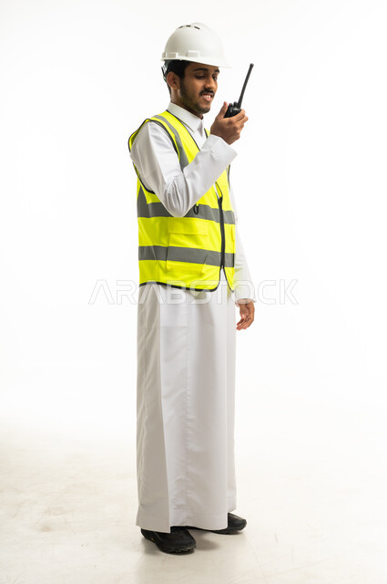 مهندس سعودي يرتدي سترة السلامة ويستخدم اللاسلكي
