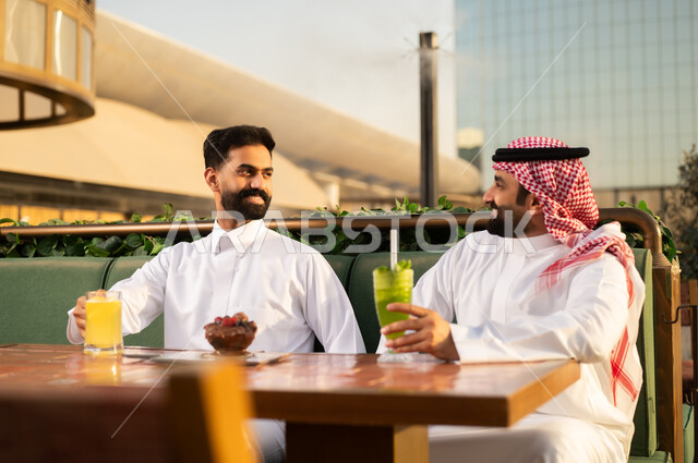رجال سعوديين يتحدثون في مطعم خارجي وقت الغروب