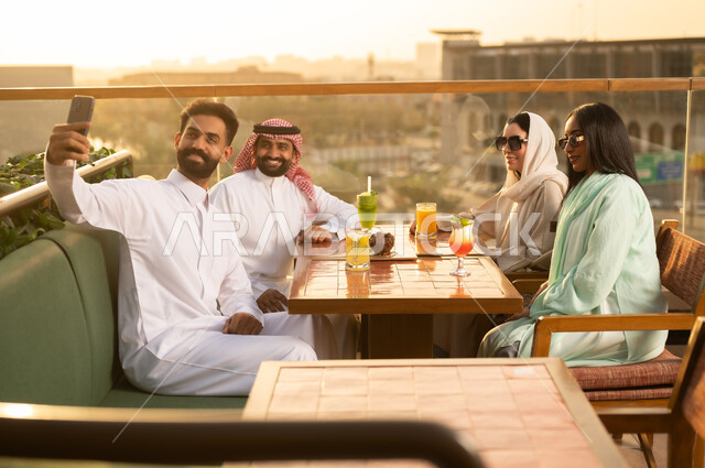 أصدقاء سعوديون في مطعم على السطح وقت الغروب