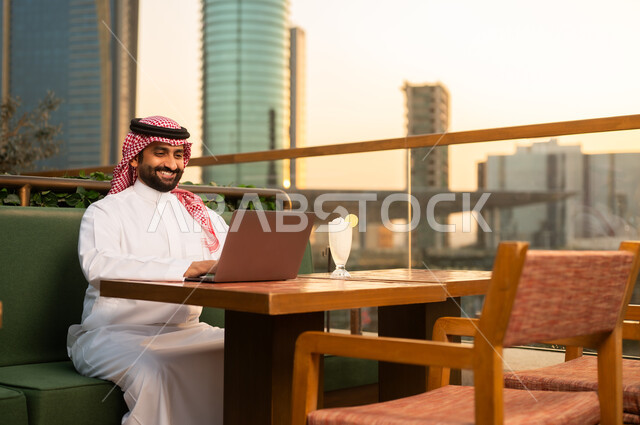 Saudi Man Using Laptop on Rooftop City Terrace