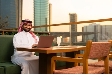 رجل أعمال سعودي يعمل على اللابتوب وقت الغروب