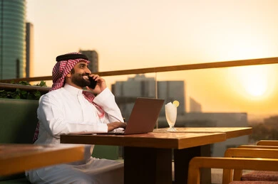 Saudi Businessman with Laptop on Rooftop at Sunset