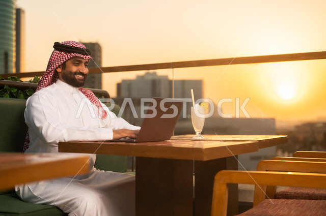 رجل سعودي يعمل على اللابتوب وقت الغروب