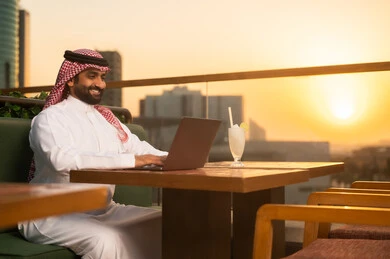 رجل سعودي يعمل على اللابتوب وقت الغروب
