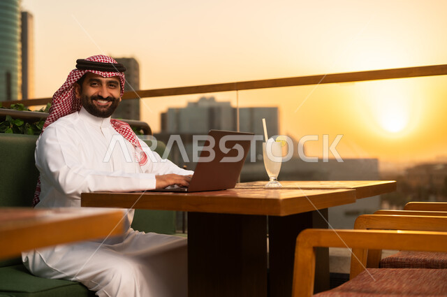 Saudi Man Using Laptop on Rooftop at Sunset