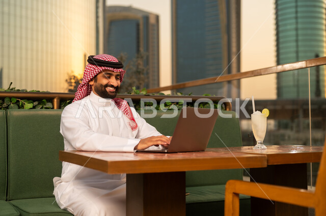 رجل أعمال سعودي يعمل على المحمول في شرفة خارجية