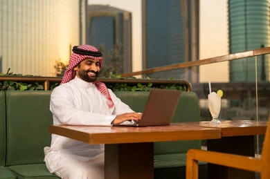 رجل أعمال سعودي يعمل على المحمول في شرفة خارجية