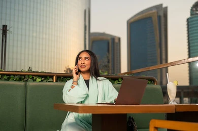 سيدة أعمال عربية مع لابتوب في مقهى خارجي