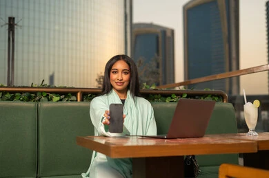 امرأة عربية تحمل هاتف ذكي في مقهى خارجي