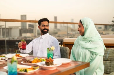 زوجان عربيان يتناولان العشاء في مطعم على السطح