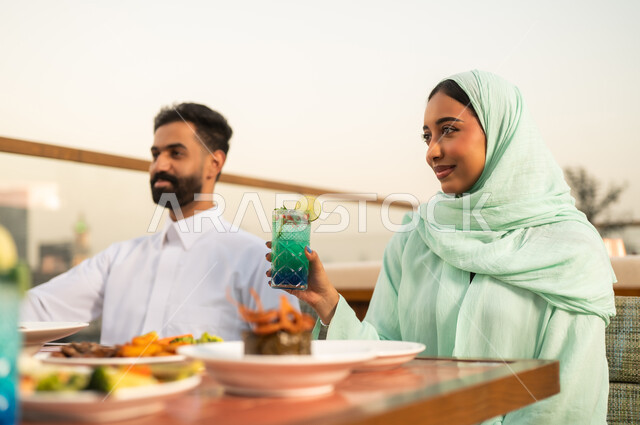 زوجان سعوديان يتناولان الطعام في شرفة مطعم خارجية