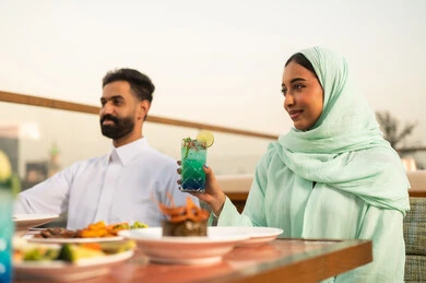زوجان سعوديان يتناولان الطعام في شرفة مطعم خارجية