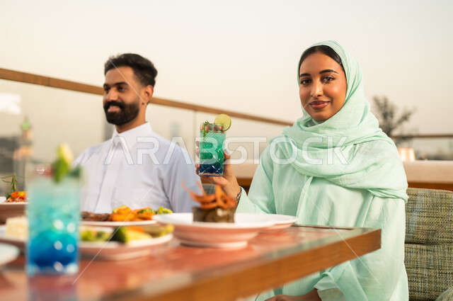 زوجان سعوديان يتناولان الطعام على سطح خارجي وقت الغروب