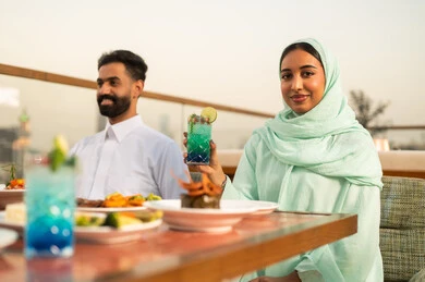 زوجان سعوديان يتناولان الطعام على سطح خارجي وقت الغروب