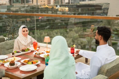 أصدقاء سعوديون يتناولون الطعام في مطعم يطل على المدينة أصدقاء سعوديون يتناولون الطعام في مطعم يطل على المدينة