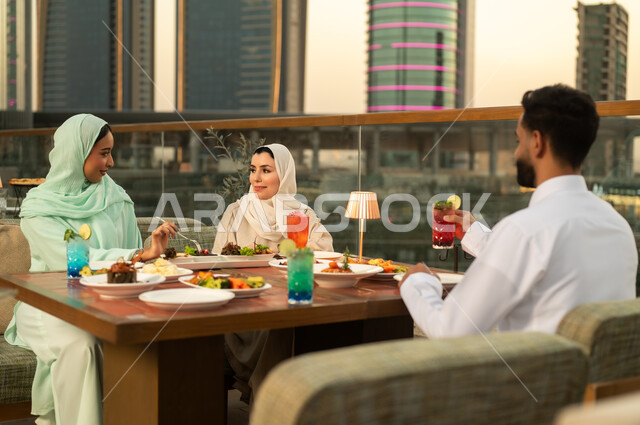 Arab Friends Dining at Rooftop Restaurant at Sunset