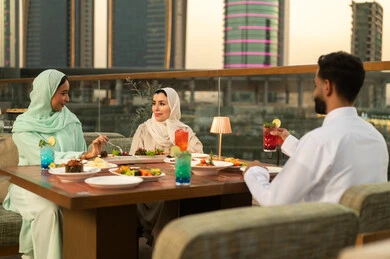 أصدقاء عرب يتناولون العشاء في مطعم خارجي وقت الغروب