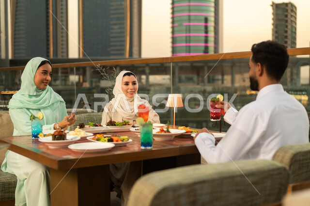 أصدقاء عرب يتناولون الطعام في مطعم بإطلالة غروب