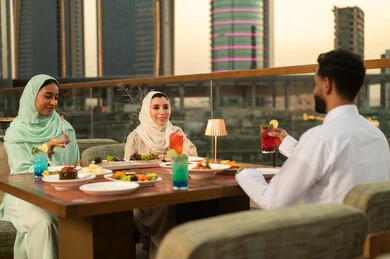 أصدقاء عرب يتناولون الطعام في مطعم روف توب