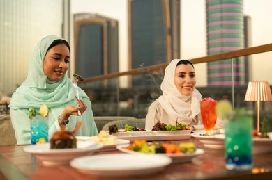 سيدات عربيات يتناولن الطعام في مطعم يطل على المدينة