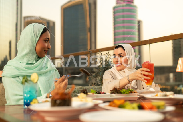 نساء عربيات يتناولن الطعام في مطعم سطحي وقت الغروب