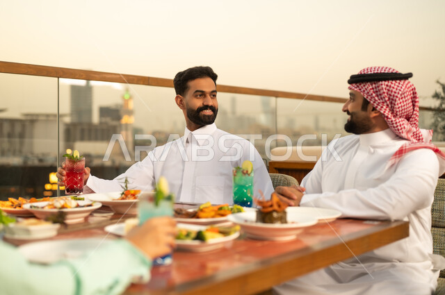 رجال سعوديون يتناولون العشاء في مطعم خارجي وقت الغروب