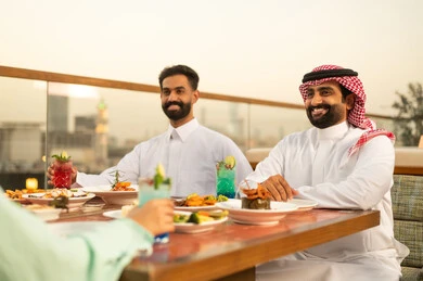 Saudi Men Dining at Rooftop Restaurant During Sunset