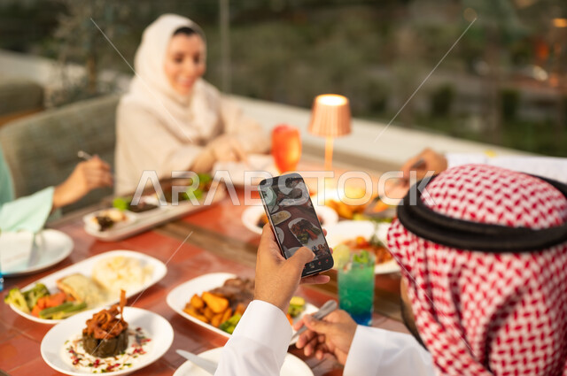 رجل سعودي يصور الأطباق العربية في عشاء خارجي